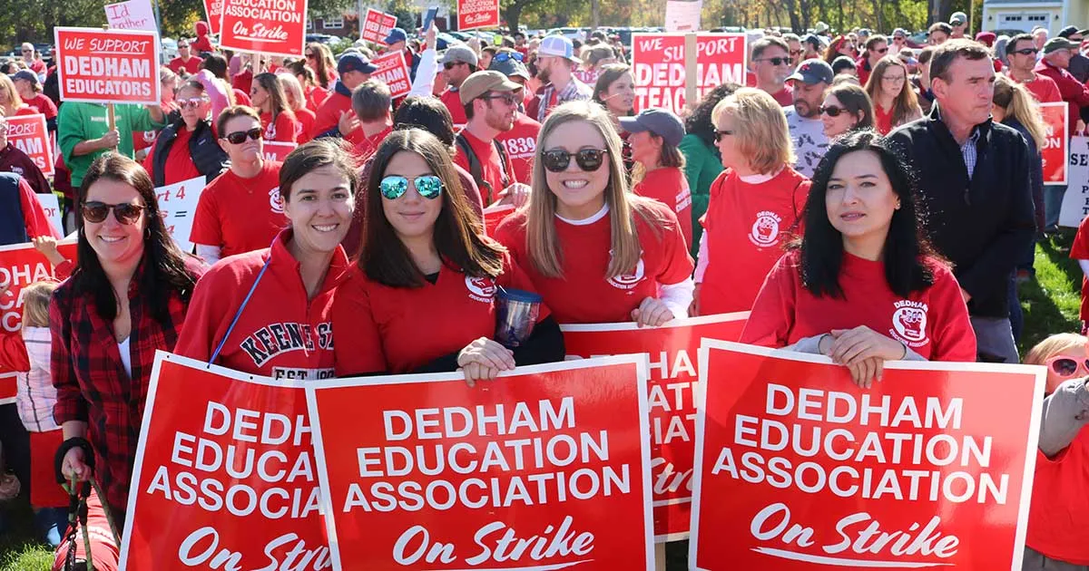 Hundreds of people, many wearing #RedForEd shirts, filled a park to hear rally speakers and march in support of a fair contract for Dedham teachers.