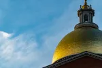 Photo of the golden dome of the Massachusetts State House with a blue sky in the background.
