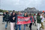 May 23 2026 Rally on Martha's Vineyard in support of a student and his father who were taken by ICE. At the forefront are three teachers carrying a banner that says "Educators United for Immigrant Rights" with the MTA logo. There are also several other people walking with them, including many students.