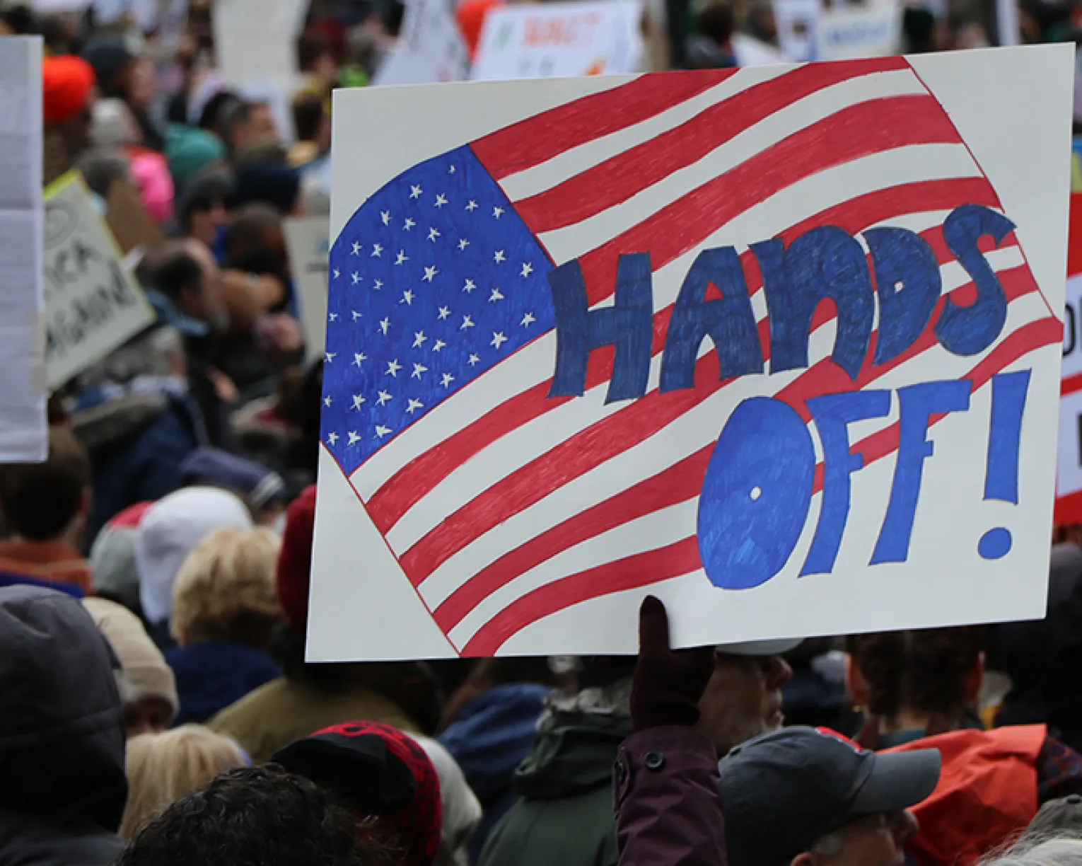 Large crowd at the 'Hands Off' rally in Boston, with many people holding signs.