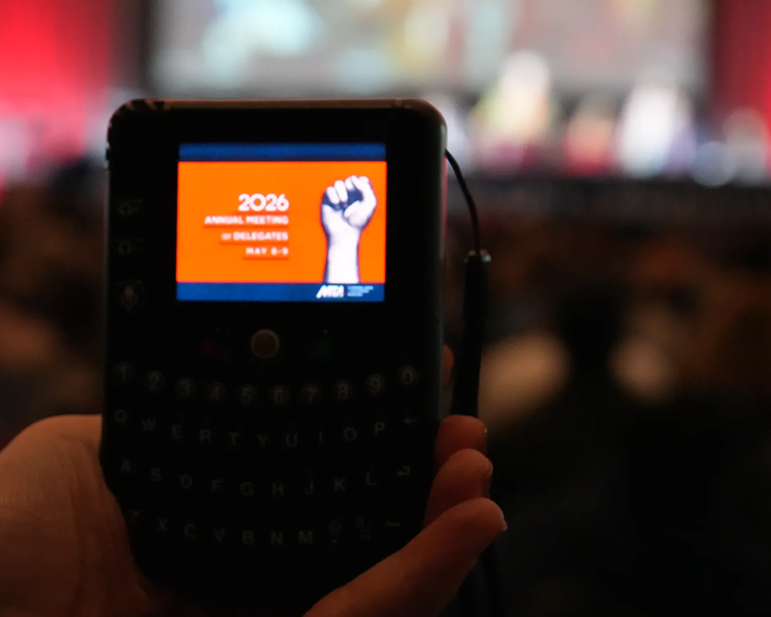 A hand holding a voting device at the 2026 Annual Meeting