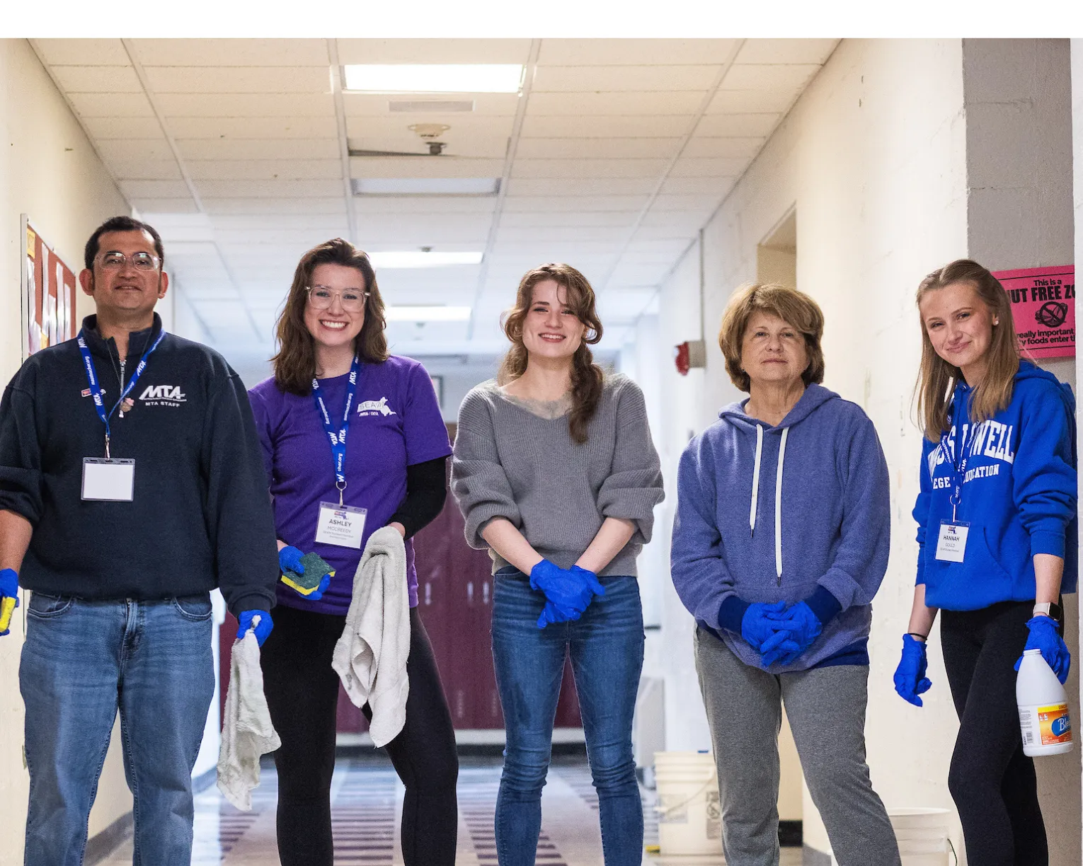Aspiring educators helped to clean a school building in Lowell. Five educators are pictured with cleaning supplies at a school.