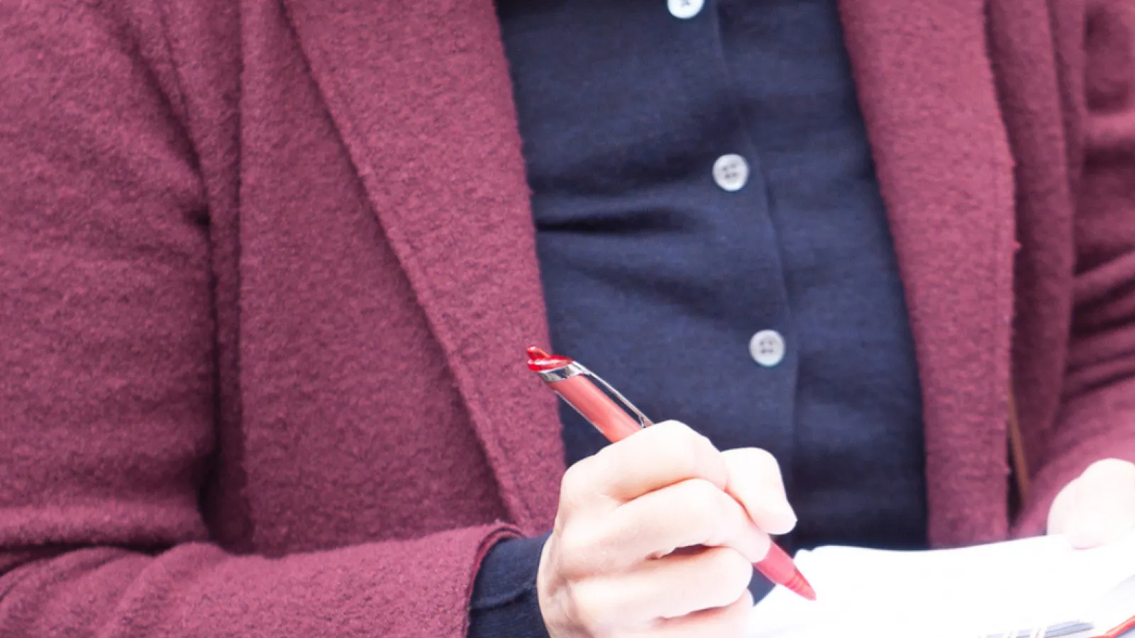 Generic photo of a female reporter who is holding a notebook and taking notes