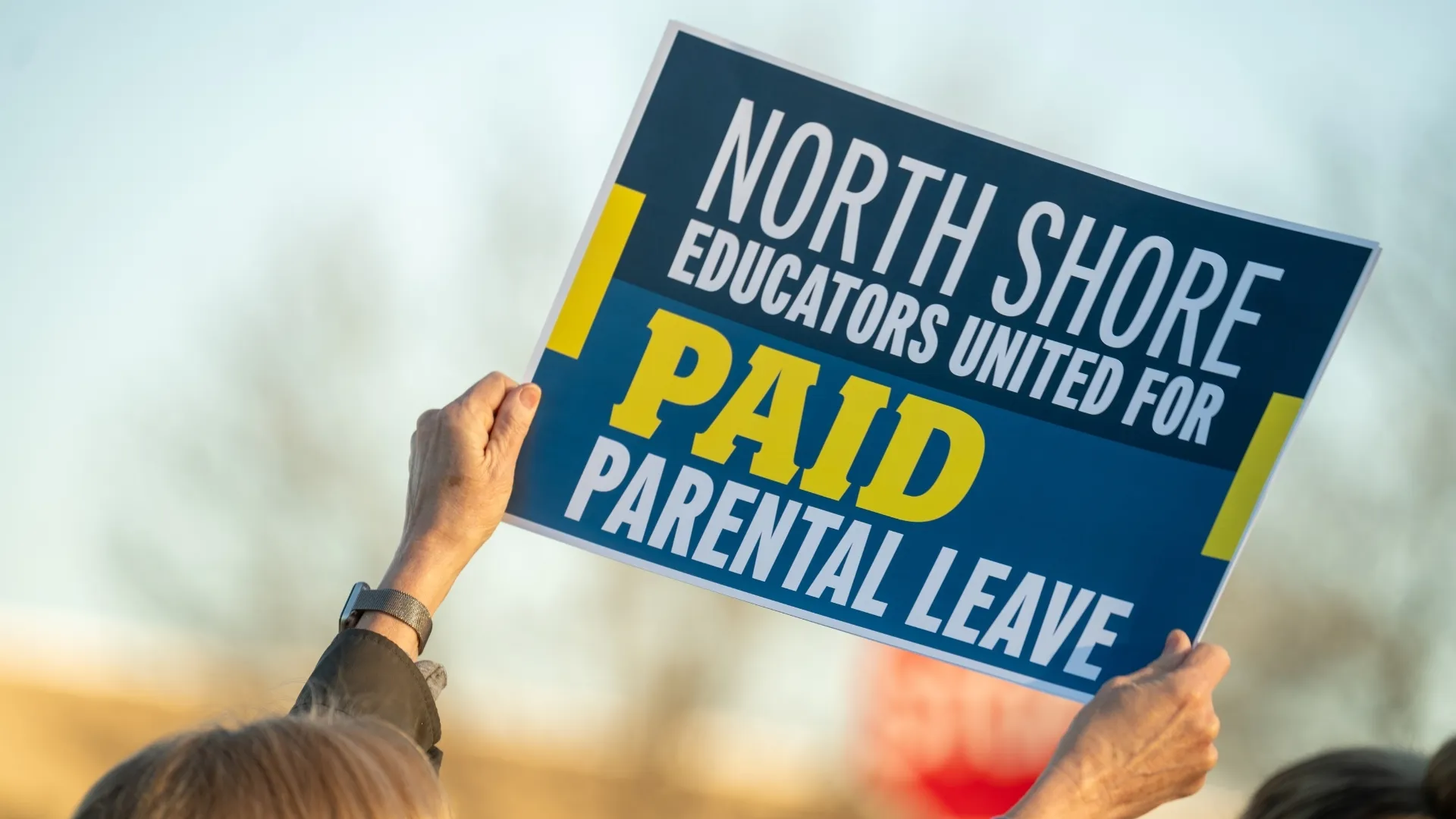 Sign reading “North Shore Educators United for Paid Parental Leave”
