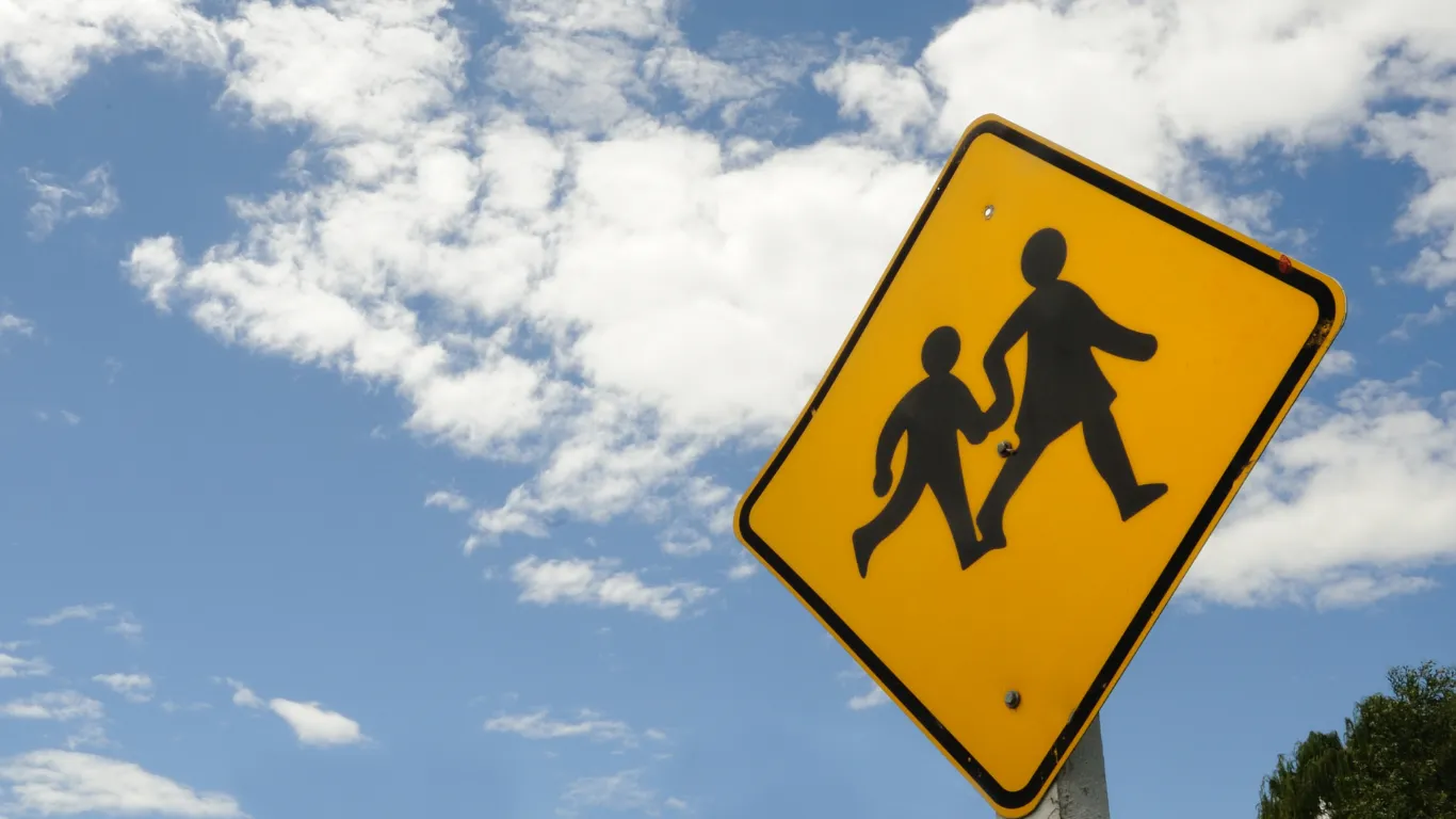 School crossing sign against a cloudy blue sky.