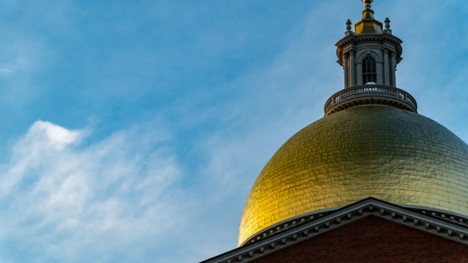 Photo of the golden dome of the Massachusetts State House with a blue sky in the background.