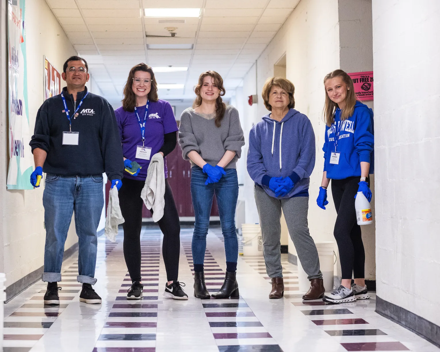 Aspiring educators helped to clean a school building in Lowell. Five educators are pictured with cleaning supplies at a school.