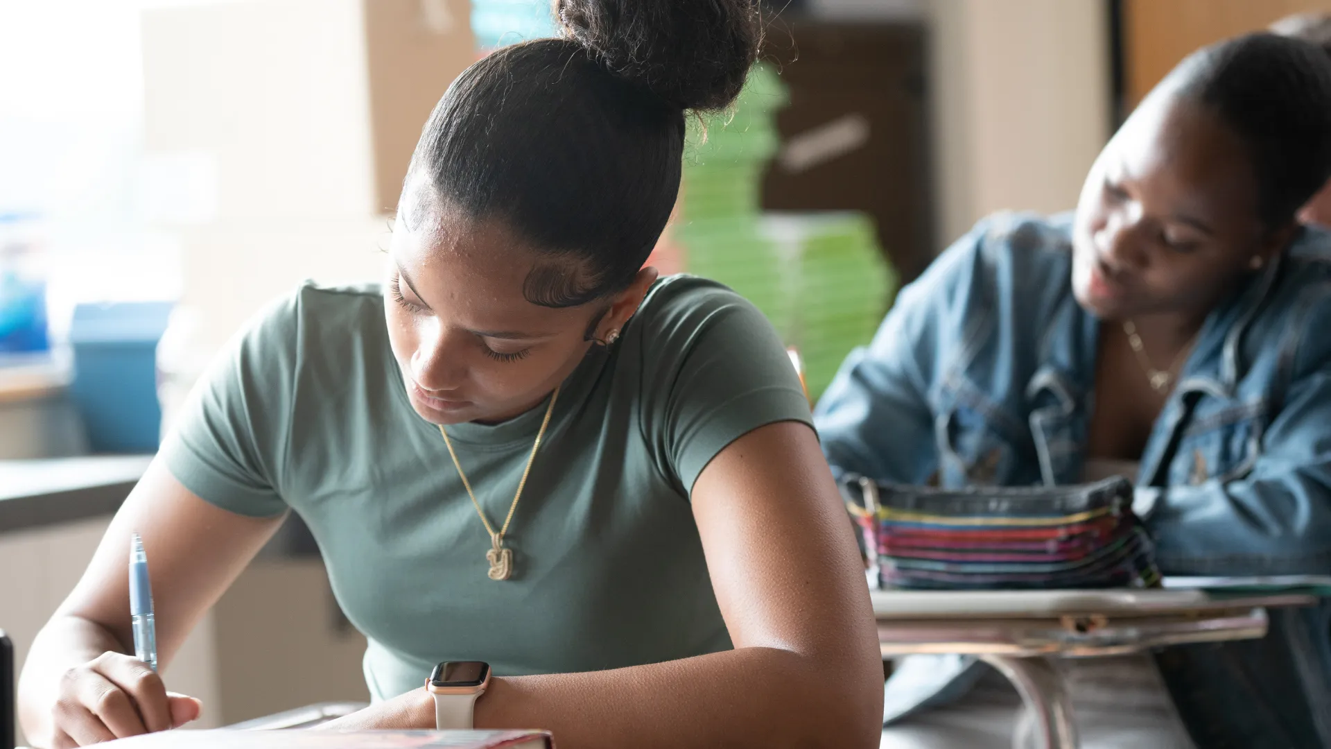 Two students working at desks in a classroom.