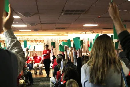 Members of the Dedham Education Association held up green cards authorizing the strike during a general membership meeting.