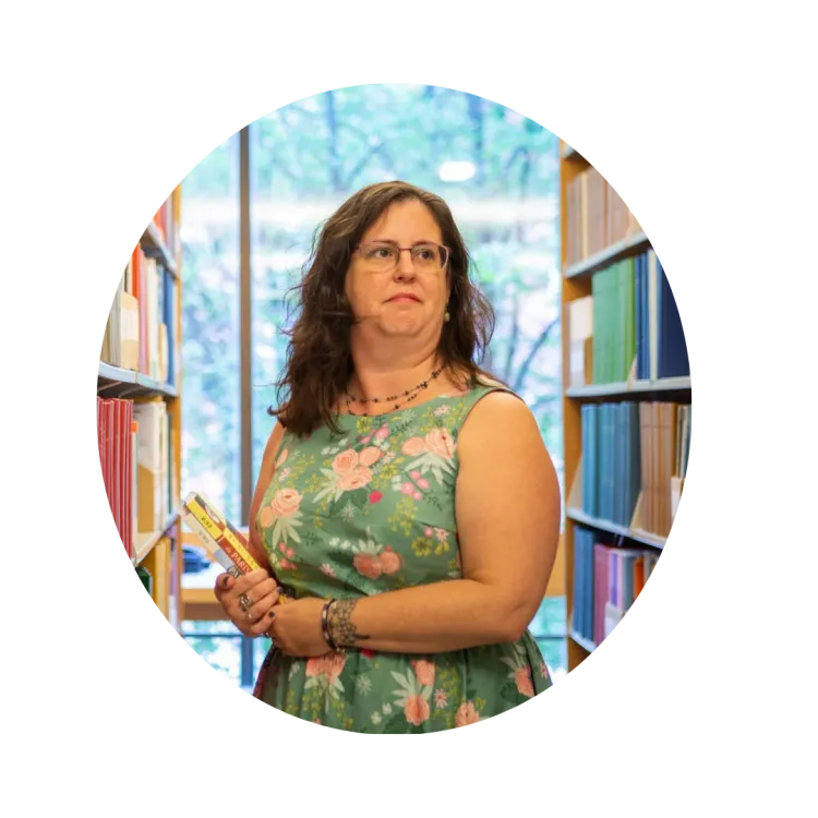 Catherine Fahey is a librarian at Salem State University. She is pictured in the middle of two shelves of books.